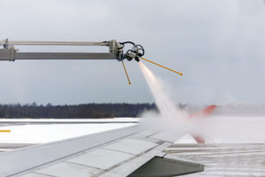 A wing of a plane is de-iced to prepare for travel.